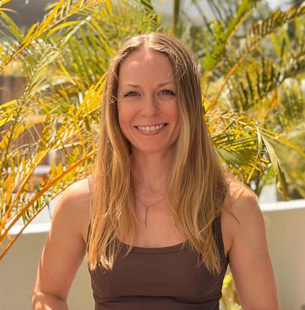 Emilie Beck Olsen smiling outdoors among palm leaves